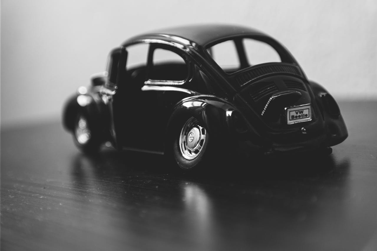 creative Black and white macro of a classic VW Beetle toy car model on a table.
